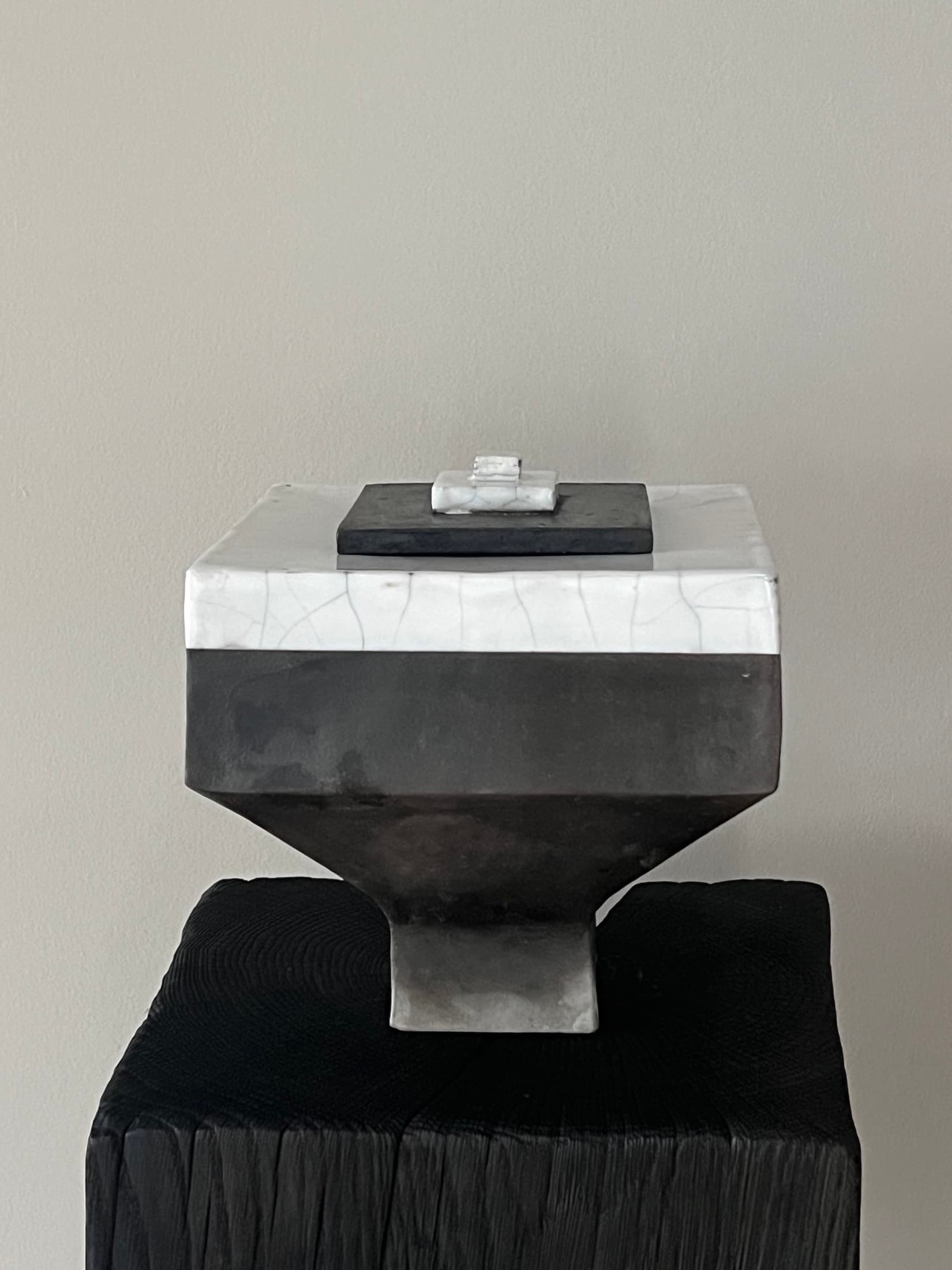 Angular lidded object on a flared foot, white crackle glaze above, matte black below