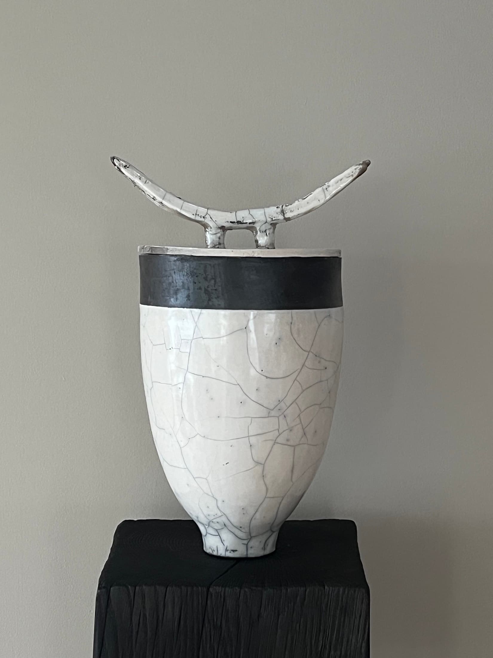 Tall lidded vase with a white crackle glaze, a black band and a horn-shaped handle