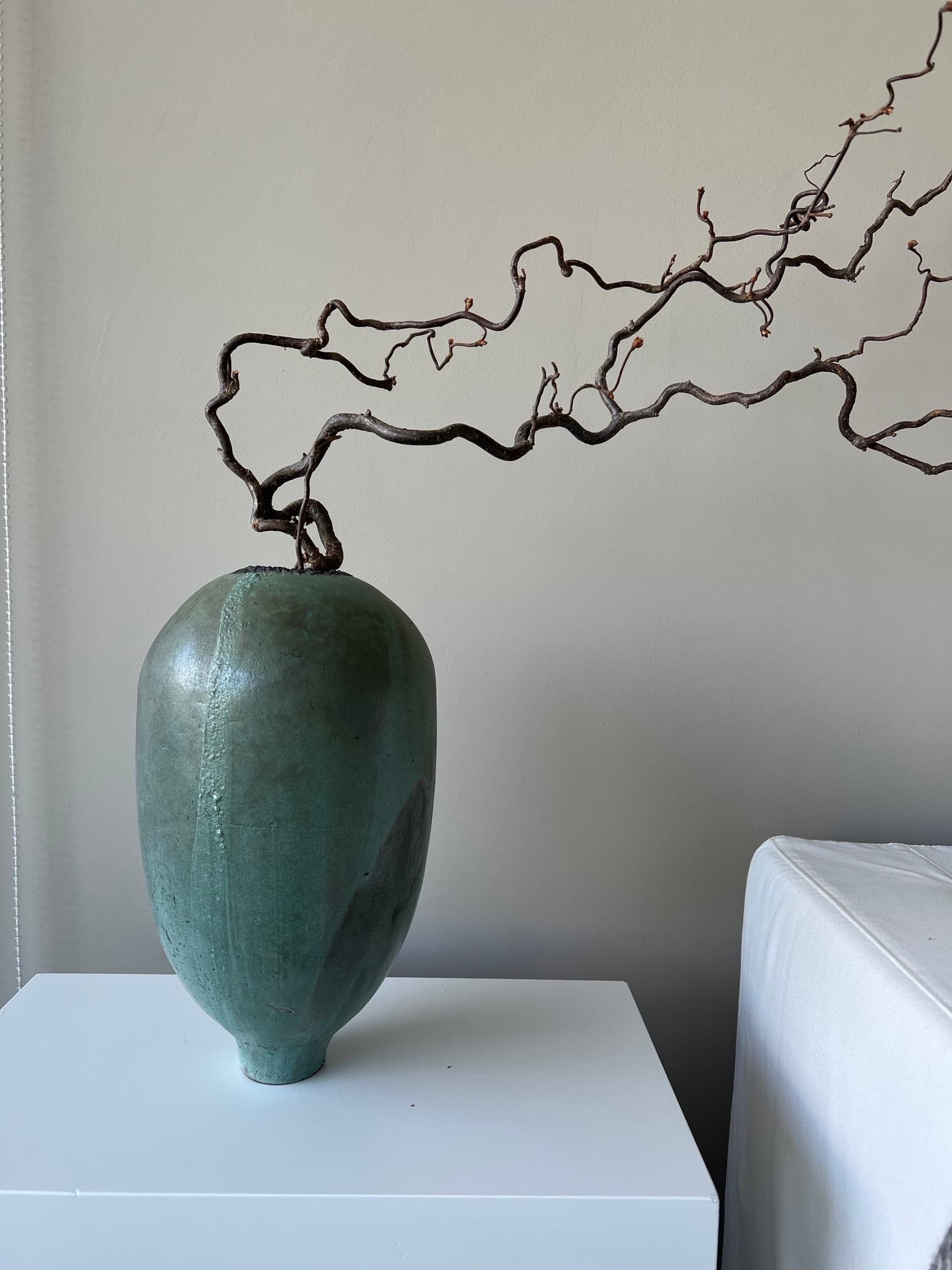 Eiförmige Vase in Grün mit knorrigem Zweig