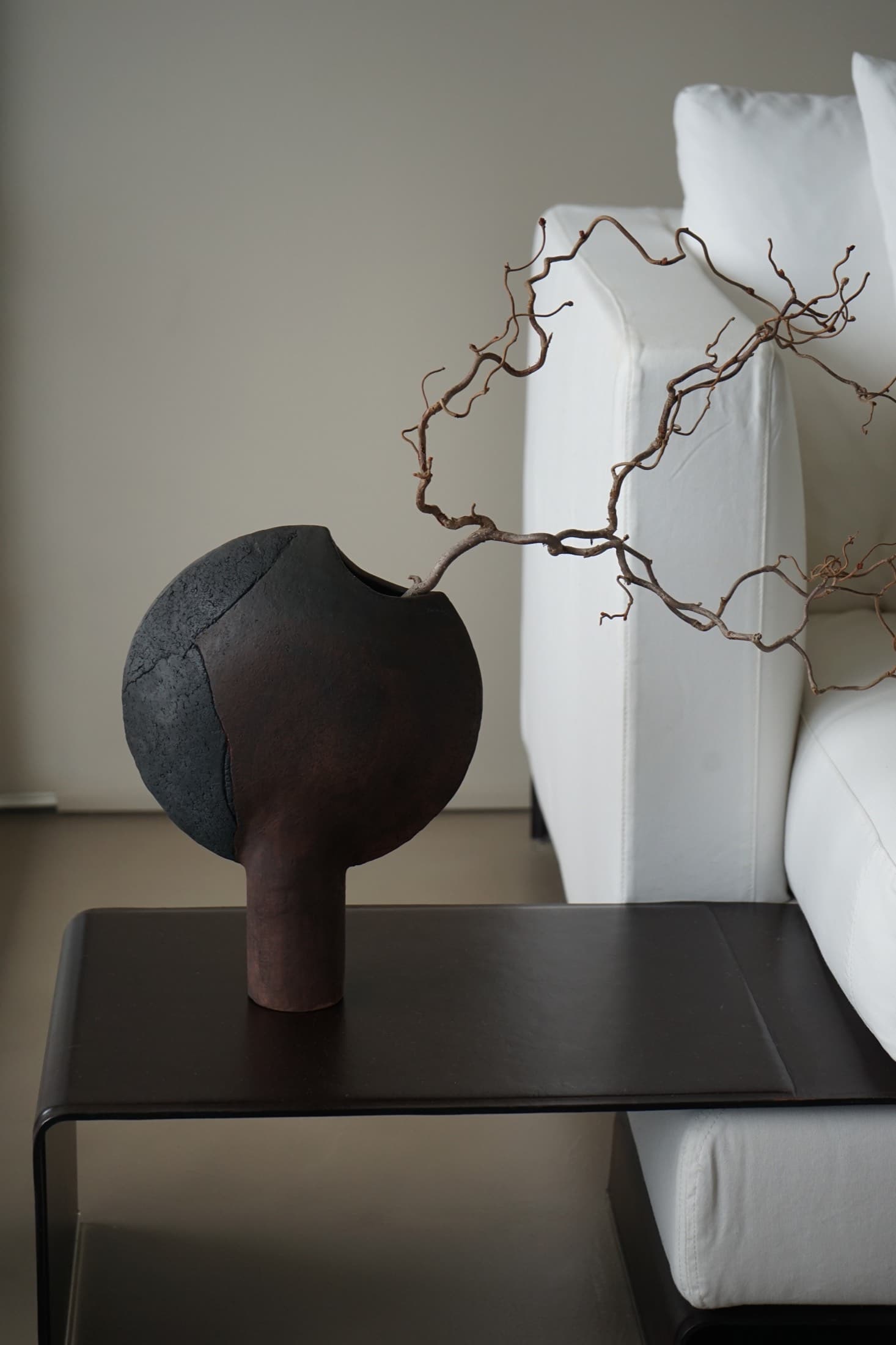 Mondförmige Vase in Schwarz-Rostbraun mit Zweig