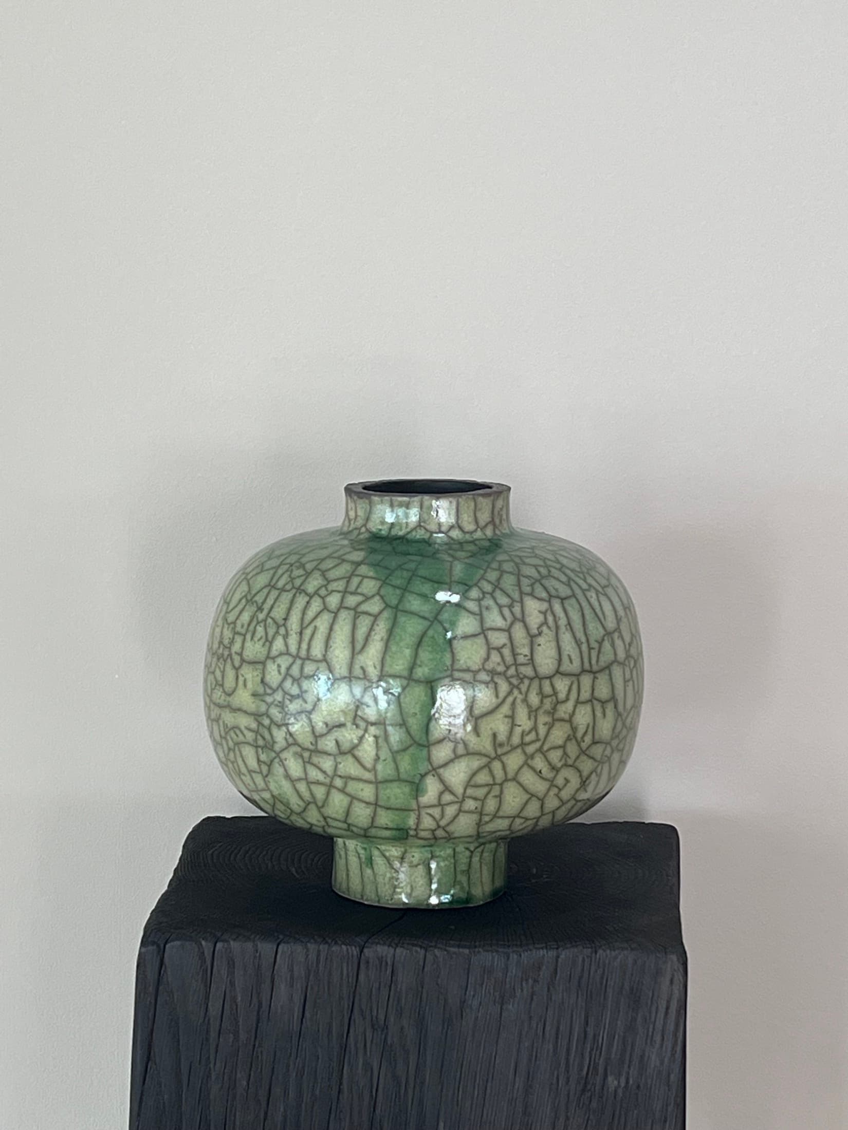 Runde Vase mit grünem Craquelé auf dunklem Sockel